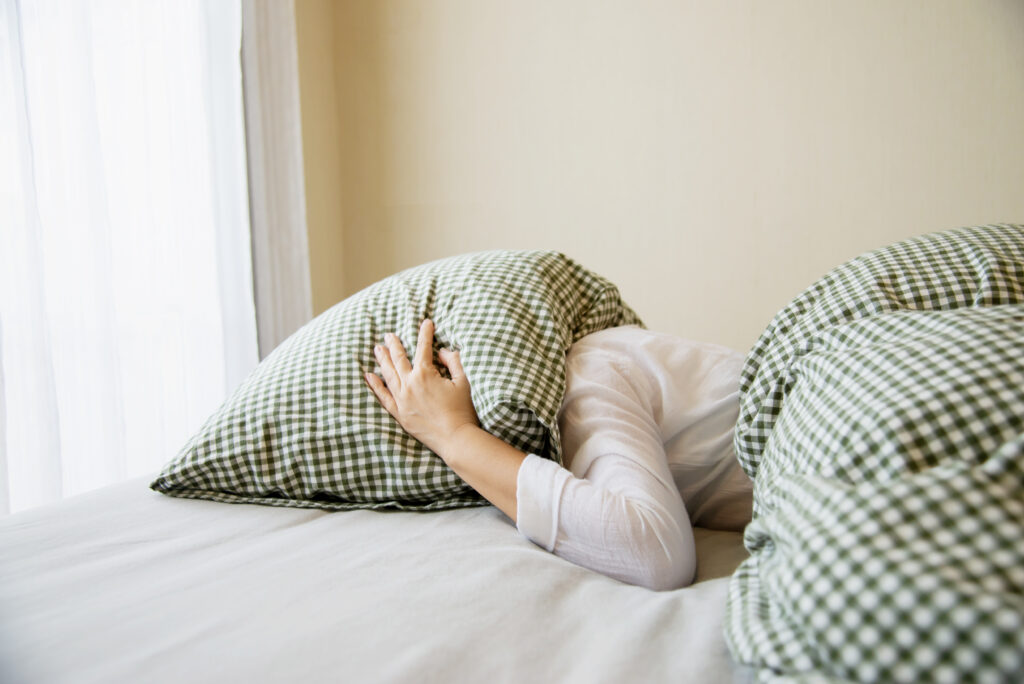 ležící žena má přikrytou hlavu polštářem, který drží